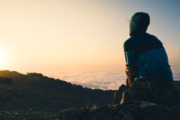 Thoughtful woman sit watch enjoy sunrise on mountain top viewpoint . Carefree tourist woman looking at sun enjoying landscape.Man Search of purpose on travels. Copy blank space