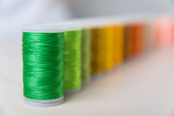 green degrade, close-ups of colored threads, dressmaker, atelier, seamstress, sewing clothes, embroidering a fabric, needle and thread, selective focus