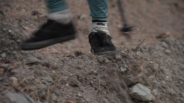 close-up of thin legs of a teenager guy walking along a narrow path in the forest, slipping on wet ground