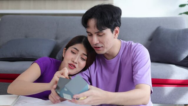 Young Asian couple planning to design a new home together,New home concept - happy couple planning new home