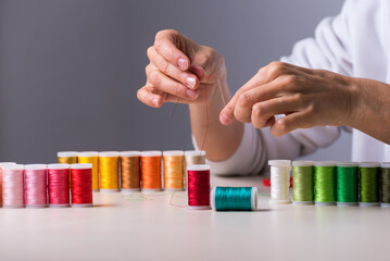 hands threading threads, colors, dressmaker, workshop, sewing, sewing clothes, fabric embroidery, selective focus