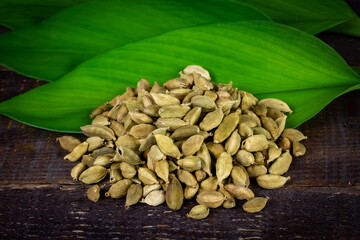Pile of Green Cardamom with fresh green leaf on rustic wooden background. Cardamom is a fragrant herb used as an ingredient for cooking. 