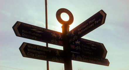 A sign post silhouetted against the sun.