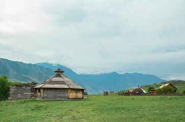 high altitude morning landscape with wooden village houses and an unfinished yurt in foggy cloudy weather