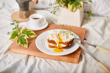 Breakfast on white bed sheets, good morning, toast with poached eggs, coffee, flowers, Hotel room early morning, honeymoon
