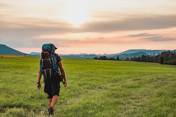 Hiker with the backpack on the green field