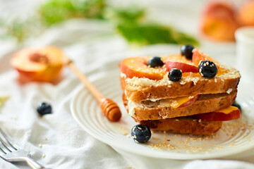 Breakfast on white bed sheets, good morning, summer french toast with cream cheese, honey, peaches and blueberries, coffee, flowers, Hotel room early morning, honeymoon