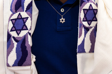 Detail of a Jewish man wearing a tallit or prayer shawl decorated with Jewish stars and a necklace...