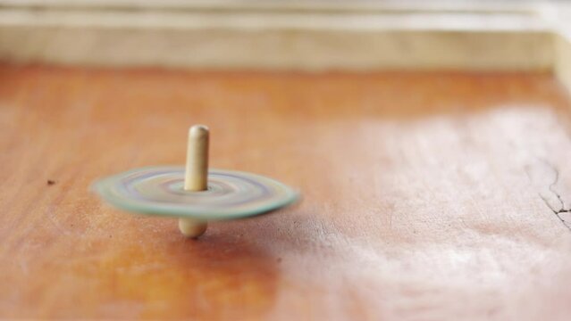 Close up and slow motion 4K of spinning top on board game with high speed rotation and and blur motion shows the retro or vintage game for entertaining kid or child in leisure time.