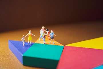 Miniature people, group of children standing on tangram puzzle background using as family and...