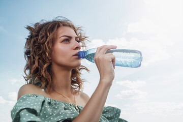 Beautiful girl drinks water on the beach.