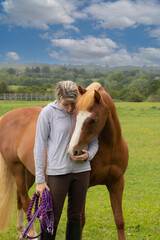 Close up of pretty young woman and her lovely chestnut pony, horse sharing a loving moment in field in rural Shropshire.
