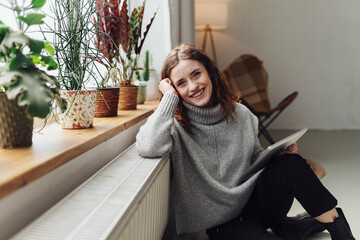 Young woman leaning against radiator with computer tablet in hand - 524091610
