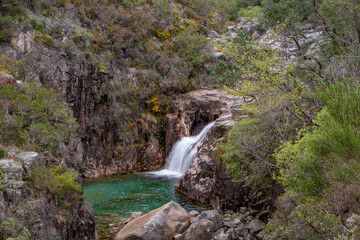Fototapeta na wymiar Small waterfall and mountain river green pond
