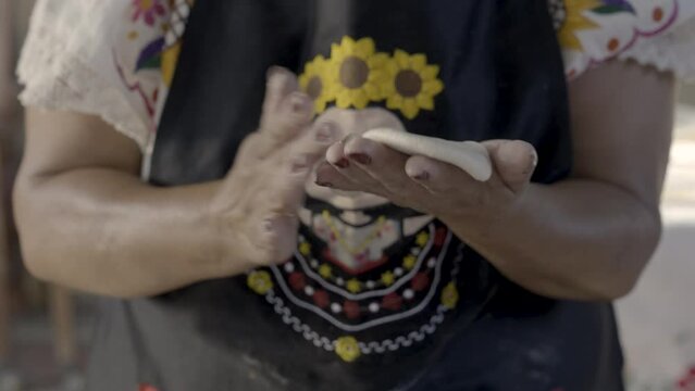 Indigenous Mexican woman's hands preparing a huarache with masa. 