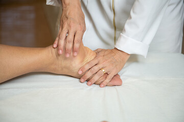 Close up em mãos de massagista aplicando massagem terapêutica no pé de um paciente.