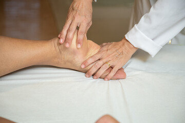Fototapeta na wymiar Close up em mãos de massagista aplicando massagem terapêutica no pé de um paciente.