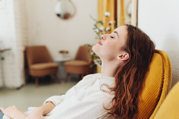 Young woman relaxing in armchair with closed eyes - 524094292