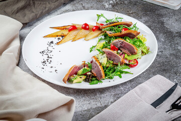 Salad with tuna, avocado, arugula greens, candied pear and cherry tomatoes