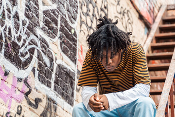 Young handsome stylish black man with natural hair dreadlocks. Afroamerican guy.Stairs,wall painted...