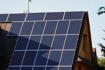 Panele solarne na skośnym dachu budynku mieszkalnego.