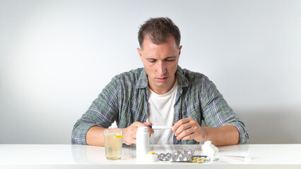 A man checks the temperature during illness - flu and cold, treatment with medications