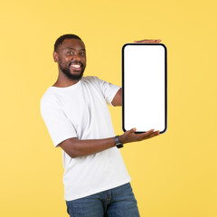 African Guy Holding Cellphone With Large Blank Screen, Yellow Background