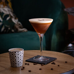 espresso martini cocktail with foam and three coffee beans over wood table with coffee cup