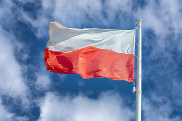 flag of poland against blue sky and white clouds