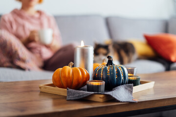 Autumn, fall cozy mood composition for hygge home decor. Small pumpkins, burning candles on tray...