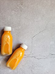 Two bottles of orange juice on a white concrete background with copy space. A nutritious cocktail. The concept of healthy eating. Fitness drink. Energy drink after sports.