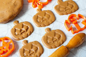 Cutting Halloween gingerbread in shape of pumpkin lantern