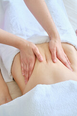 Close-up of a professional massage therapist doing a belly massage to a woman. Relaxation, body care, beauty, healthy lifestyle, tranquility, anti-stress help. Spa treatments for the body