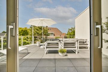 Neat paved patio with sitting area and small garden near wooden fence