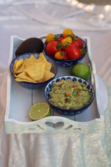 Guacamole home made with tortilla chips ripe red and yellow tomatoes and lime served