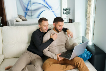 Obraz premium Couple of men watching movie on laptop at home