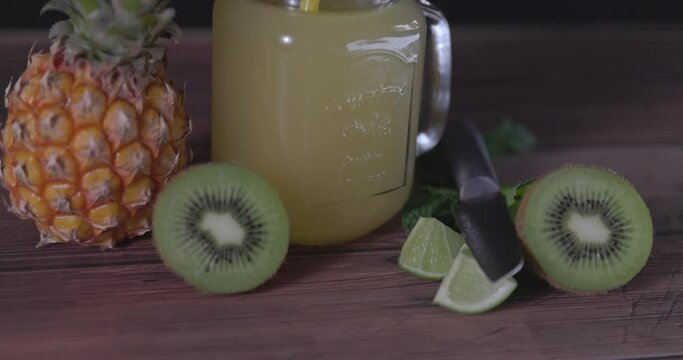 Natural juice mug with pineapple, kiwi and lime. With blurred woman's body in background.