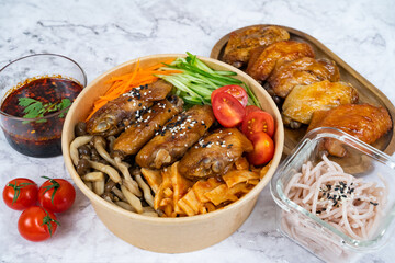BAKED MARMITE MID WING with noodle, tomato, carrot, cucumber and sauce served in a bowl isolated on grey background side view healthy korean food