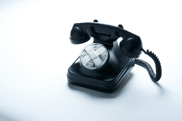 Close-up antique black bakelite telephone with strips on the dial and white background