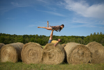 caucasian couple doing stunts on straw bales in France