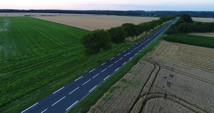 Vue a&eacute;rienne d'une route bord&eacute;e d'arbres traversant des champs, &agrave; la tomb&eacute;e de la nuit en Seine-et-Marne