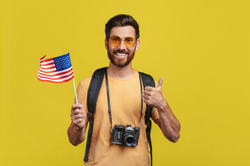 Travelling abroad concept. Male tourist holding USA flag and showing thumb up, middle aged man ready for vacation