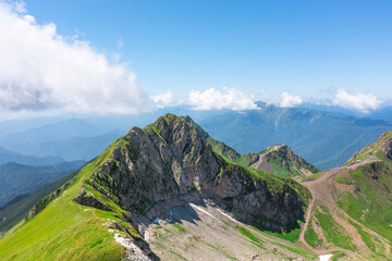 Fototapeta premium Majestic aerial view of the top of the mountain range and mountain cirque valley with shady snow slopes.