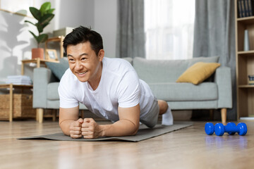 Motivated asian man having workout at home - Powered by Adobe