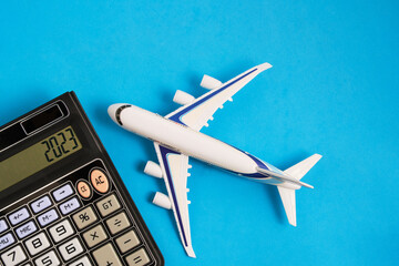 Airplane model and calculator blue background.Concept of costs or expenses for air travel.Budget of...