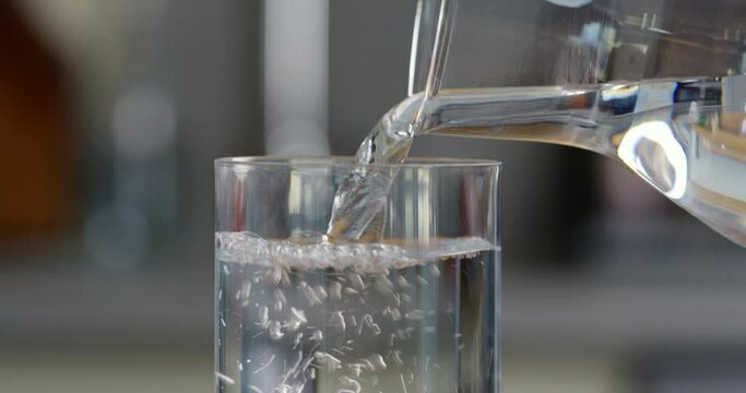 Pouring water into glass in the kitchen
