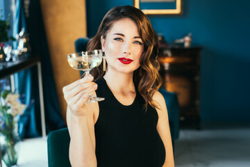 Portrait of posh elegant woman in evening dress with a glass of champagne in the luxury interior....