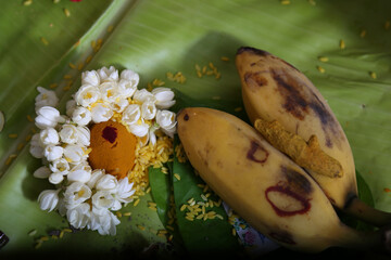 religious pooja items flower, banana, coconut on a green leaf
