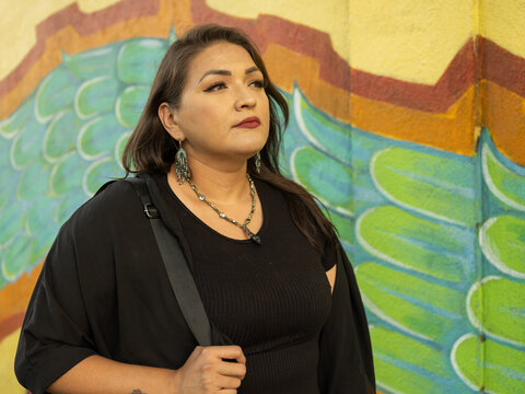 Native teacher poses in front of school mural