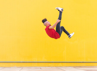 Man doing parkour trick near yellow wall